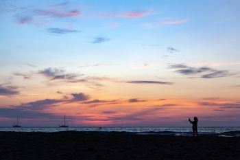 Asian woman selfie with smartphone on the beach while beautiful sky after sunset