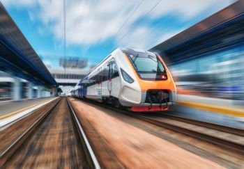 High speed train in motion on the railway station at sunset. Modern intercity passenger train with motion blur effect on the railway platform. Industrial. Railroad in Europe. ?ommercial transportation
