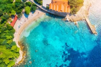 Aerial view with beautiful sea coast, sandy beach, clear blue water, hotels and green trees at sunset. Summer tropical landscape. Top view of blue sea, buildings, rocks and forest. Luxury resort 