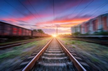 Railroad and beautiful sky with clouds at sunset with motion blur effect in summer. Industrial landscape with freight train, railway station and blurred background.  Railway platform in speed motion