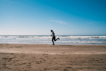 Portrait of an athletic man running at the beach. Sport, fitness and healthy lifestyle.