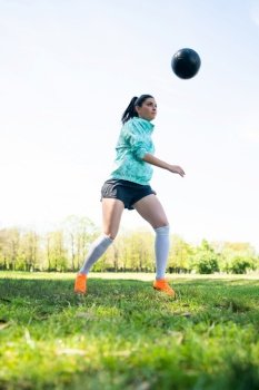 Portrait of young woman practicing soccer skills and doing tricks with the football ball. Soccer player juggling the ball. Sports concept.