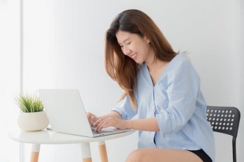 Beautiful young of Asian woman using a laptop  while sitting working at home, Asia women smile while typing work from home 