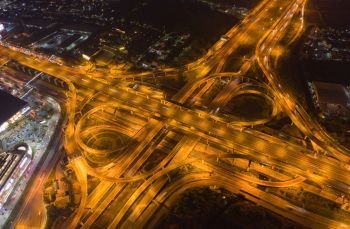 Aerial view of cars driving on highway junctions. Bridge roads shape number 8 or infinity sign in connection of architecture concept. Top view. Urban city, Bangkok at night, Thailand.