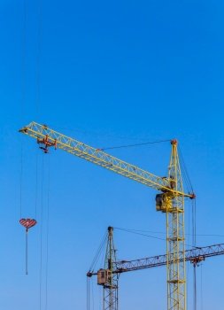 Two cranes with a light blue sky background. Construction site. Old construction equipment. 