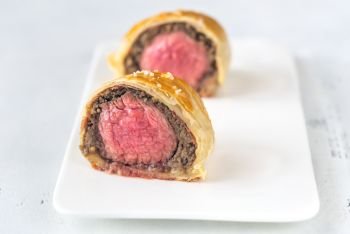 Portion of beef Wellington on the white plate: cross section
