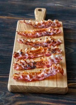 Fried bacon strips on the wooden board