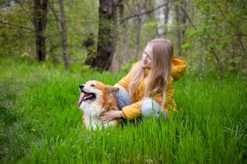 friends - little girl with corgi dog walking outdoors at sunny spring day
