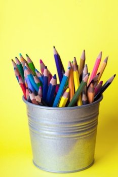 bucket with pencils on a
 yellow  background