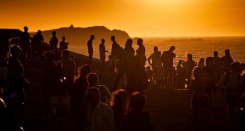crowd of people watching sunset by the sea