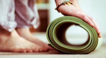 woman rolling a yoga mat at home
