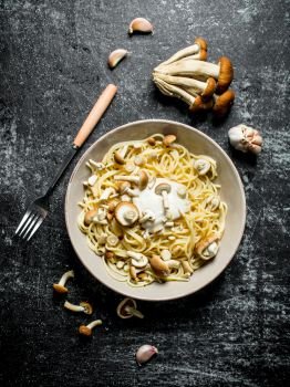 Pasta in bowl with mushrooms and garlic. On black rustic background. Pasta in bowl with mushrooms and garlic.
