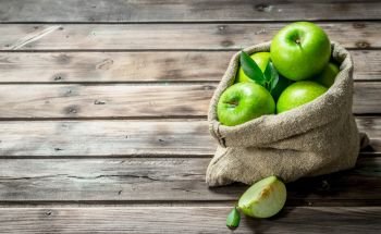 Green apples and Apple slices in an old bag. On grey wooden background.. Green apples and Apple slices in an old bag.