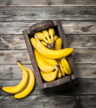 Lots of bananas in a black wooden box. On a black wooden background.. Lots of bananas in a black wooden box.