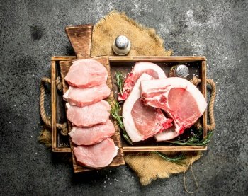 Raw pork meat with herbs and spices in a tray. On rustic background.. Raw pork meat with herbs and spices in a tray.