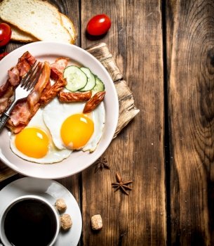 Fresh Breakfast with Cup of coffee, fried bacon with eggs and tomatoes. On a wooden table.. Fresh Breakfast with Cup of coffee
