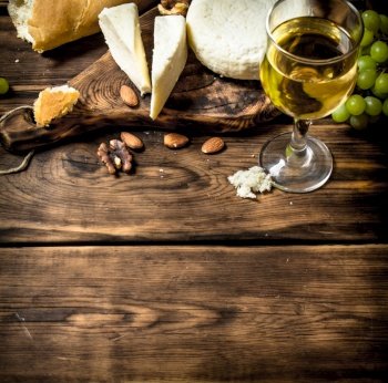 Goat cheese with white wine and nuts. On a wooden table.. Goat cheese with white wine and nuts.