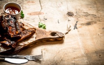 Barbecued ribs with tomato sauce. On wooden background.. Barbecued ribs with tomato sauce.