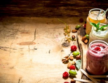 Berry smoothie with wild berries and nuts. On wooden background.. Berry smoothie with wild berries and nuts.