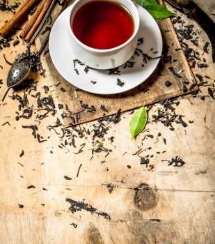 Tea with leaves and cinnamon. On wooden background.. Tea with leaves and cinnamon.