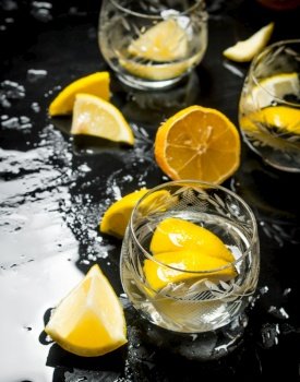 Glasses with vodka and lemon. On a black wooden background.. Glasses with vodka and lemon.