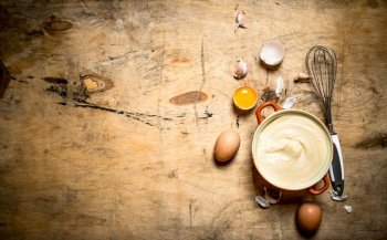 Mayonnaise in bowl with ingredients for cooking. On wooden background.. Mayonnaise in bowl with ingredients for cooking.