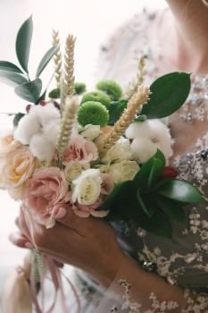 Bride in a wedding dress holding a wedding bouquet in her hands. Bride in a wedding dress holding a wedding bouquet in her hands close-up