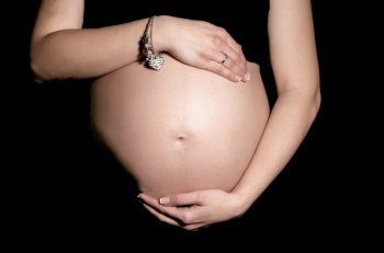 Horizontal view of pregnant belly in dark background
