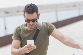 Young man wearing sunglasses using phone outdoors