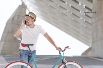Young handsome guy with a bicycle holding a mobile phone in his hand