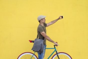 Hipster man taking a selfie . He is commuting, he has a fixed gear bike. Lifestyle, travel and sustainability concepts.
