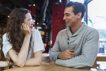 Side view of loving couple looking at each other sitting in a coffee shop