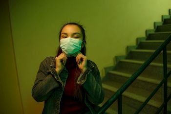 portrait of an Asian young woman. stairwell of the hospital. the girl wears a mask to avoid getting infected with the virus