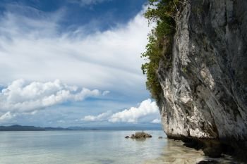 Tropical white limestone cliff over the calm sea in Kri island, Raja Ampat, Indonesia
