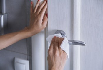 Woman cleaning the door handle with disinfecting wipe