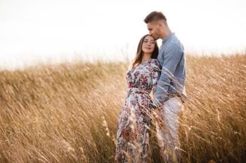 beautiful young couple hugging in a field with grass at sunset. stylish man and woman having fun outdoors. family concept. copy space. beautiful young couple hugging in a field with grass at sunset. stylish man and woman having fun outdoors. family concept. copy space.
