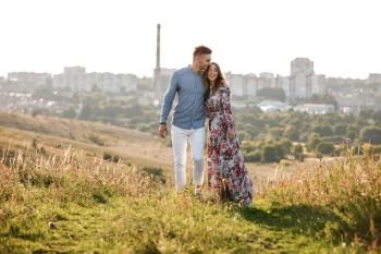 beautiful young couple in love hugging and smiling outdoors on city background. stylish romantic woman with long hair have a good time with man. copy space.. beautiful young couple in love hugging and smiling outdoors on city background. stylish woman have a good time with man. copy space