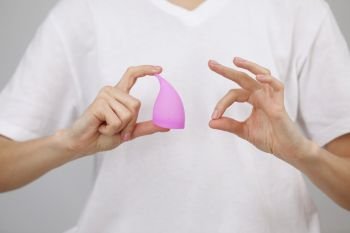 Young woman hand holding menstrual cup. Women health concept, zero waste alternatives. Ok Sign Fingers. Young woman hand holding menstrual cup. Women health concept, zero waste alternatives. Ok Sign Fingers.