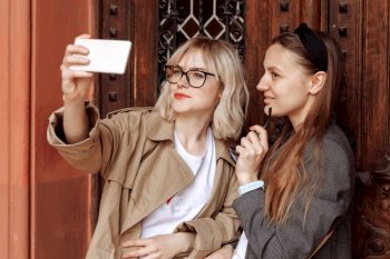 young girls taking selfies on the phone. selfie photos for social media on smartphone on the street background. Surprise face, emotions. young girls taking selfies on the phone. selfie photos for social media on smartphone on the street background. Surprise face, emotions.
