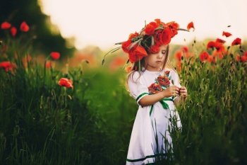 beautiful little girl with a wreath of poppies on head. cute child in wild poppies field.. beautiful little girl with a wreath of poppies on head. cute child in wild poppies field
