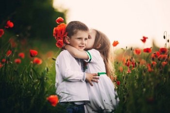 Children’s love, a little boy and a girl, amicably spend time, laugh and smile, and kiss in the flowering field of poppies.. Children’s love, a little boy and a girl, amicably spend time, laugh and smile, and kiss in the flowering field of poppies