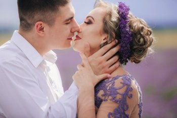 portrait of Young couple in love kissing in a lavender field on summer. girl in a luxurious purple dress.. portrait of Young couple in love kissing in a lavender field on summer. girl in a luxurious purple dress