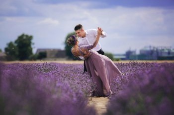 Young couple in love hugging and dancing in a lavender field on summer. girl in a luxurious purple dress.. Young couple in love hugging and dancing in a lavender field on summer. girl in a luxurious purple dress