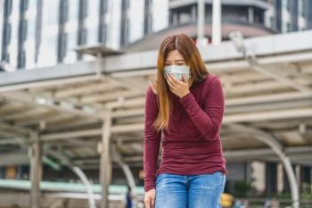 Asian woman wearing safety medical face mask for prevent Coronavirus or Covid19 Outbreak, coughing  when travel to work in business downtown, Health care and infection concept