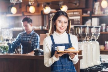 Asian Coffee shop owner serving bakery cake and coffee cup to customer in coffee shop, Small business owner and startup in coffee shop and restauran, waitress and barista concept