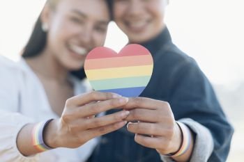 Close up hand of LGBTQ couple holding rainbow heart. LGBT rights concept.