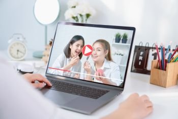 Young Asian woman beauty vlogger video online is showing make up on cosmetics products and live video on laptop. e-learning concept.