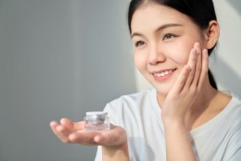 Smile Asian woman skin beauty and hand holding a product cream bottle for spa products and make up. The skin is smooth and beautiful.
