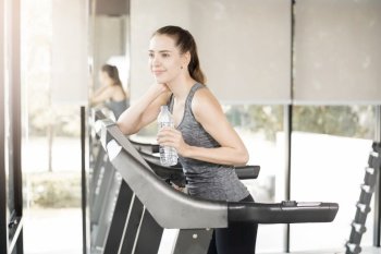 Pretty young sport woman is drinking water on treadmill in gym, Healthy lifestyle 