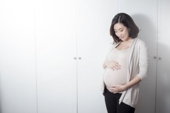  Beautiful asian pregnant woman expecting  baby and touching her belly 